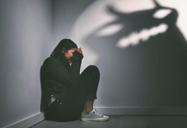 PTSD in New York A Distressed Woman Sits Curled up in the Corner of a Room